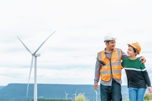 Engineer with his son on a wind farm atop a hill or mountain in the rural. Progressive ideal for the future production of renewable, sustainable energy. Energy generation from wind turbine.