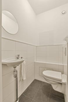 a bathroom with white tiles and gray flooring on the walls, there is a mirror above the toilet bowl