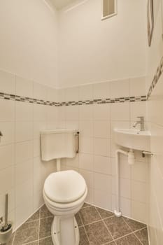 a white toilet in a small bathroom with tile flooring and walls that have black and white tiles on them