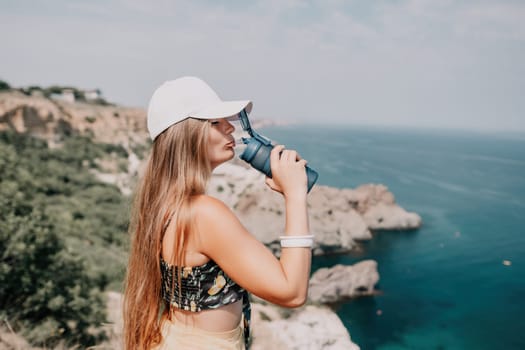 Woman travel sea. Happy tourist taking picture outdoors for memories. Woman traveler looks at the edge of the cliff on the sea bay of mountains, sharing travel adventure journey.