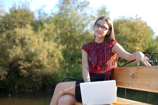 Girl on bench work with laptop in autumn park