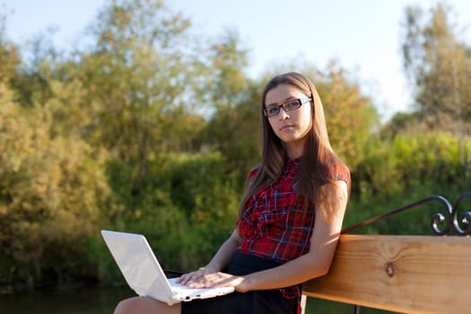 Girl on bench work with laptop in autumn park