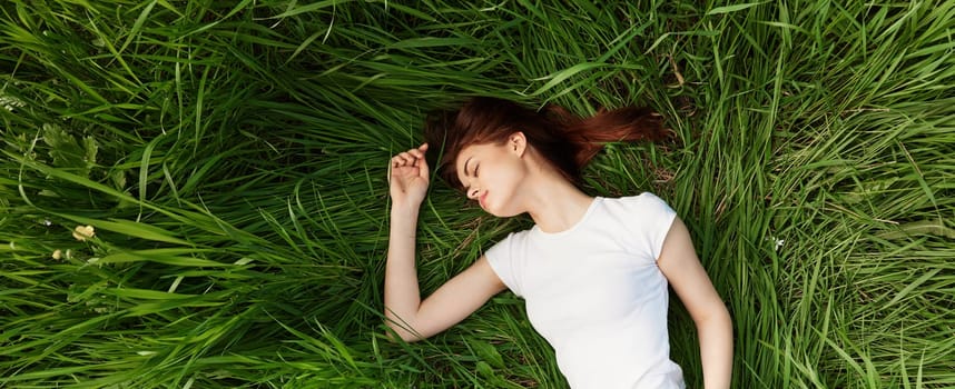 peaceful, happy woman lies in green tall grass. High quality photo