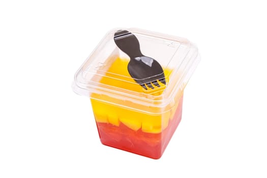 Grapefruit, mango and raspberry jelly in a plastic cup with a fork on the lid, on a white background. High quality photo