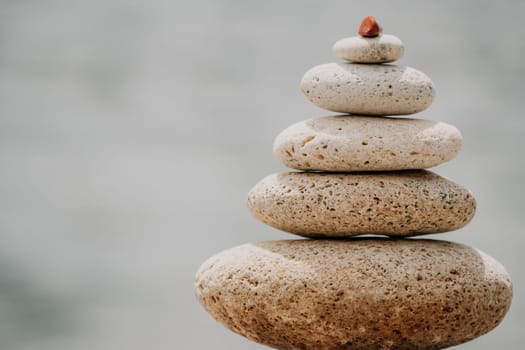 Pyramid stones on the seashore with warm sunset on the sea background. Happy holidays. Pebble beach, calm sea, travel destination. Concept of happy vacation on the sea, meditation, spa, calmness.