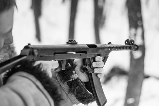 retro photo of soldier who shoots in the winter forest from machine gun