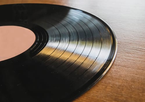 vinyl record lies on brown wooden table.