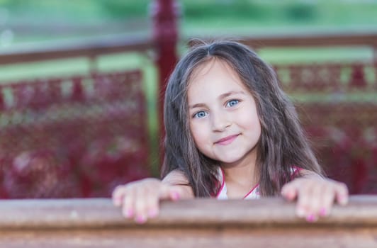 Pretty Girl in a colorful dress holding onto the railing in the yard.