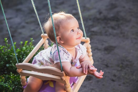 cute beautiful baby swinging in the yard on a swing sticking.