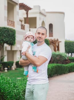 father holding adorable child at home in the garden.