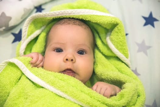 beautiful newborn baby wrapped in a green towel after bathing.