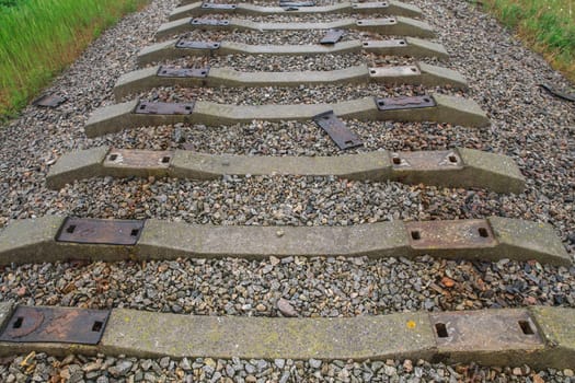 Old dismantled railway with grass on the side of the road.