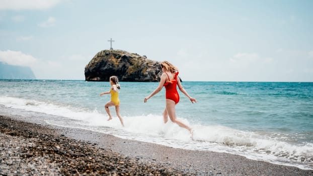 Happy loving family mother and daughter having fun together on the beach. Mum playing with her kid in holiday vacation next to the ocean - Family lifestyle and love concept.