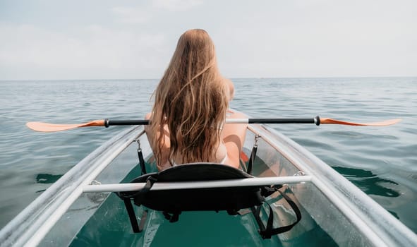 Woman in kayak back view. Happy young woman with long hair floating in transparent kayak on the crystal clear sea. Summer holiday vacation and cheerful female people having fun on the boat.