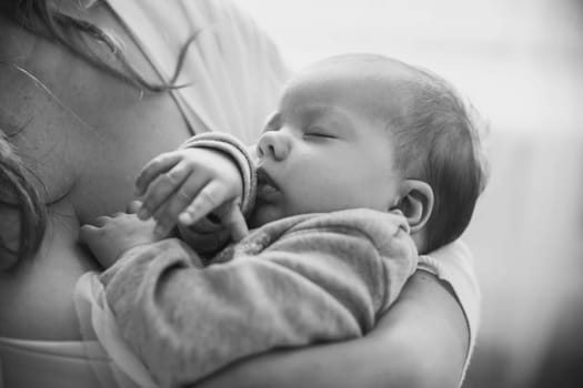 Black and white photo. Mother holds her sleeping baby.