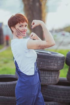 attractive woman mechanic in overalls shows biceps.