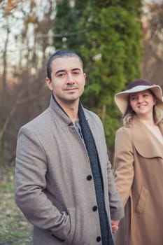 Married couple in coat walking in the autumn park.