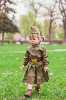 Sad baby girl in Soviet military uniform.