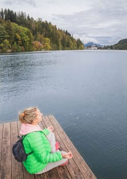 Girl meditate on the lake in the mountains.