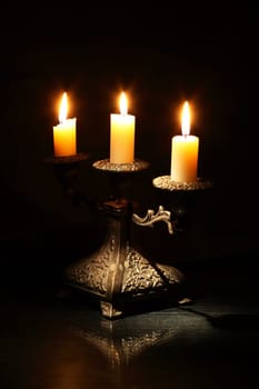 Nice vintage candlestick with lighting candles on dark background