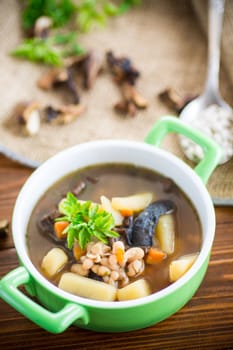 mushroom hot soup with beans in a bowl, on a rustic burlap tablecloth.