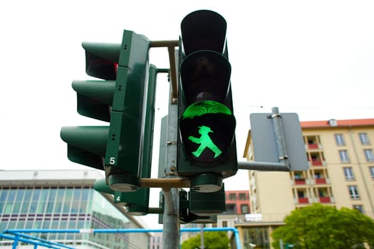Traffic light for pedestrians with the figure of a walking man, lights green.