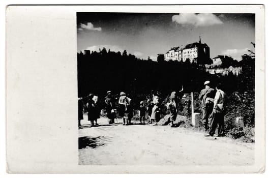 THE CZECHOSLOVAK SOCIALIST REPUBLIC - CIRCA 1950s: Retro photo shows tourists outside. The castle is on background. Vintage black and white photography.