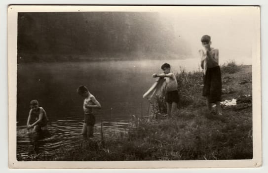 THE CZECHOSLOVAK SOCIALIST REPUBLIC - CIRCA 1950s: Retro photo shows a group of boys goes into the river. Summer vacation view. Vintage black and white photography.