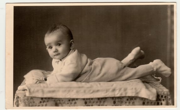 BEROUN, THE CZECHOSLOVAK REPUBLIC - MARCH 1, 1944: Retro photo shows toddler, lie prone. Vintage black and white photography.