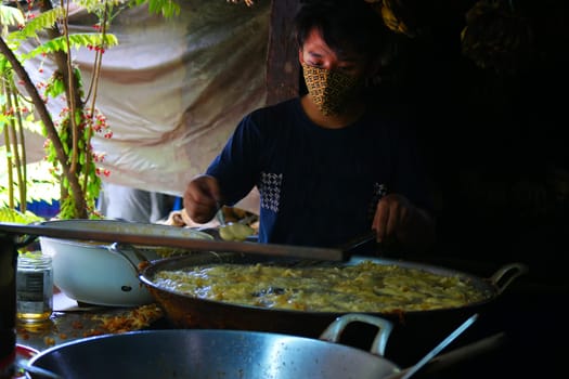 October 3, 2020. Yogyakarta, Indonesia. A man deep frying sliced banana or banana fritter with hot oil in the pan. Travel Photo.