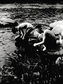 THE CZECHOSLOVAK SOCIALIST REPUBLIC - CIRCA 1950s: Retro photo shows boys at the bank of the river. Summer vacation theme. Vintage black and white photography.