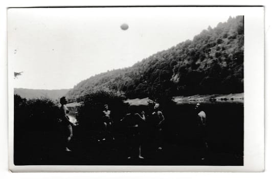 THE CZECHOSLOVAK SOCIALIST REPUBLIC - CIRCA 1950s: Retro photo shows people on the vacation. Young people play with ball. Summer holiday theme. Vintage black and white photography.