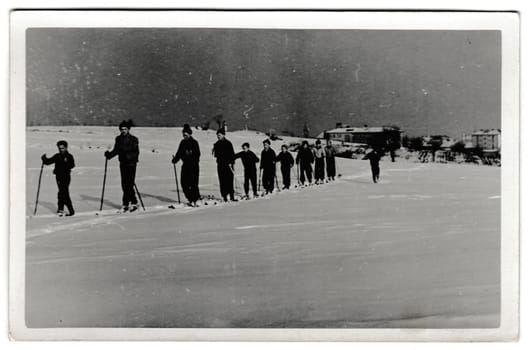 THE CZECHOSLOVAK SOCIALIST REPUBLIC - FEBRUARY 24, 1956: Retro photo shows cross-country skiers outside. Winter vacation theme. Vintage black and white photography.
