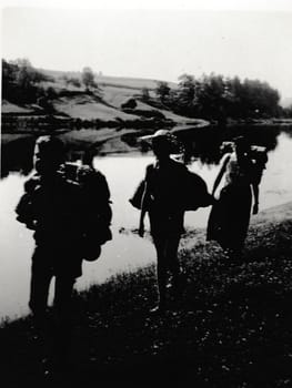 THE CZECHOSLOVAK SOCIALIST REPUBLIC - CIRCA 1950s: Retro photo shows tourists outside. Boys go alog the river bank. Vintage black and white photography.