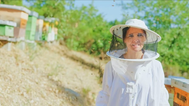 Portrait with copy space of a female beekeeper in a field with bee hives