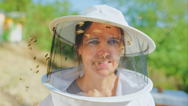 Some bees flying around the face of a beekeeper wearing protective gear in a field