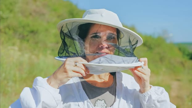 Portrait of a caucasian woman putting on a costume of a beekeeper in a field