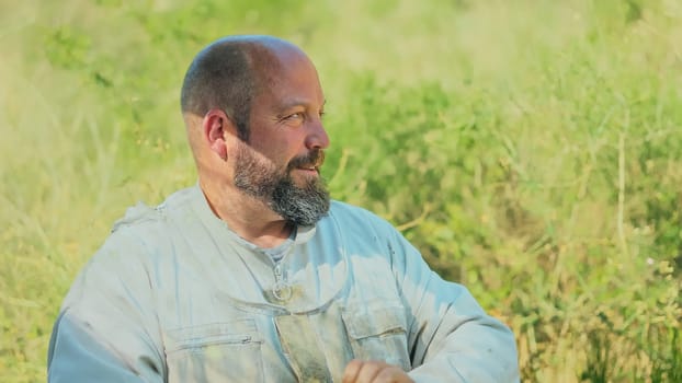 Profile of a distracted beekeeper looking aside and wearing uniform on a field