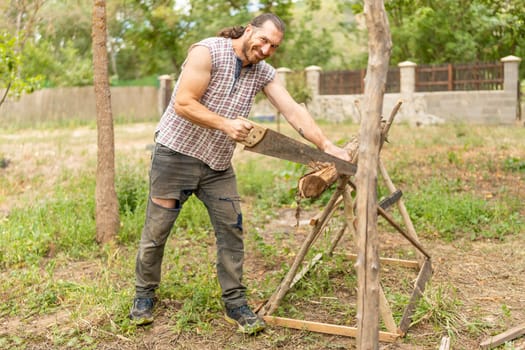 Portrait of a smiley woodcutter looking at camera while sawing wood in an garden