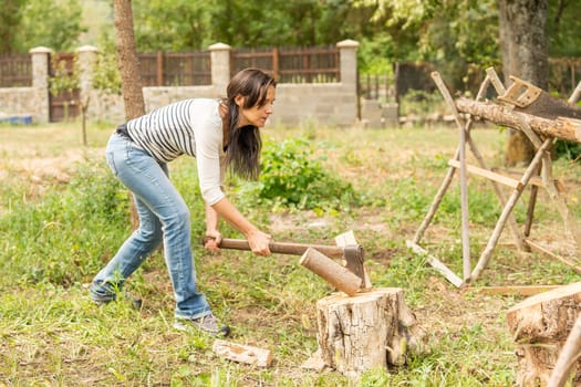 Slim and fit young woman chopping a log on a garden