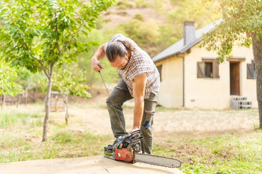 Woodcutter male ripping up a chainsaw in a garden