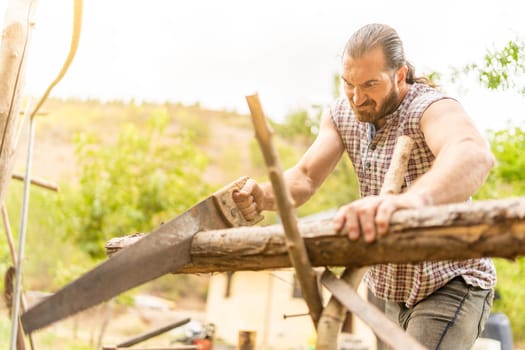 Portrait of a man making an effort to cut down a log with a hand saw