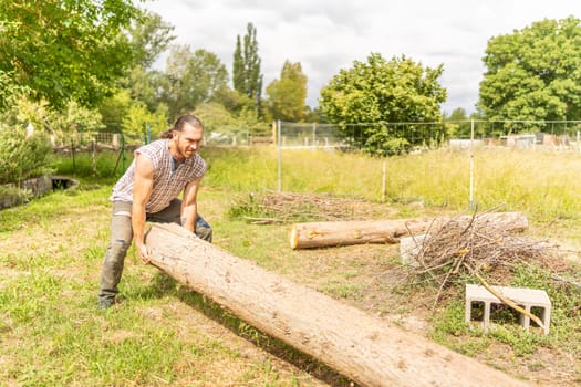 Portrait of a male woodcutter lifting a log with his bare hands in a field