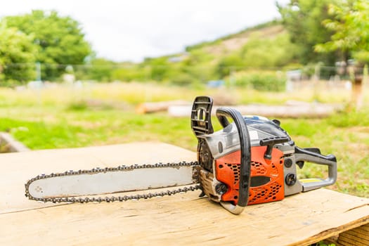 Focus on a chainsaw on a wooden table in a garden