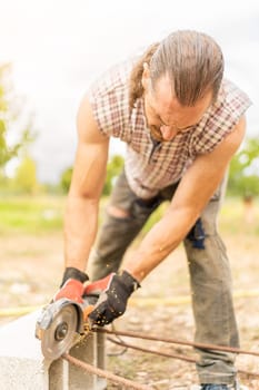 Vertical portrait of a man cutting a piece of iron using a radial saw