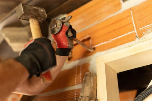 Detail of the hands of a man cutting a hole in the wall to put in wiring