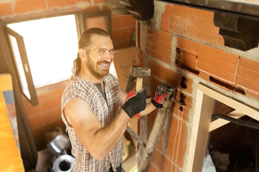 Happy man cutting a hole in the wall to put in wiring