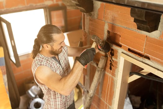 High angle view of a man cutting a hole in the wall to put in wiring