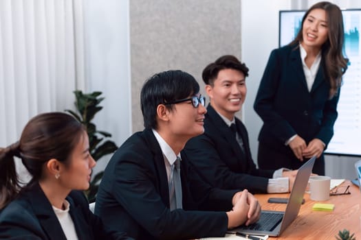 Confidence and young asian businesswoman give presentation on financial business strategy in dashboard report display on screen to colleagues in conference room meeting as harmony in workplace concept