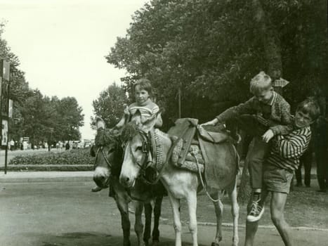 USSR - CIRCA 1970s: Retro photo shows children with donkeys in the park. Vintage black and white photography.